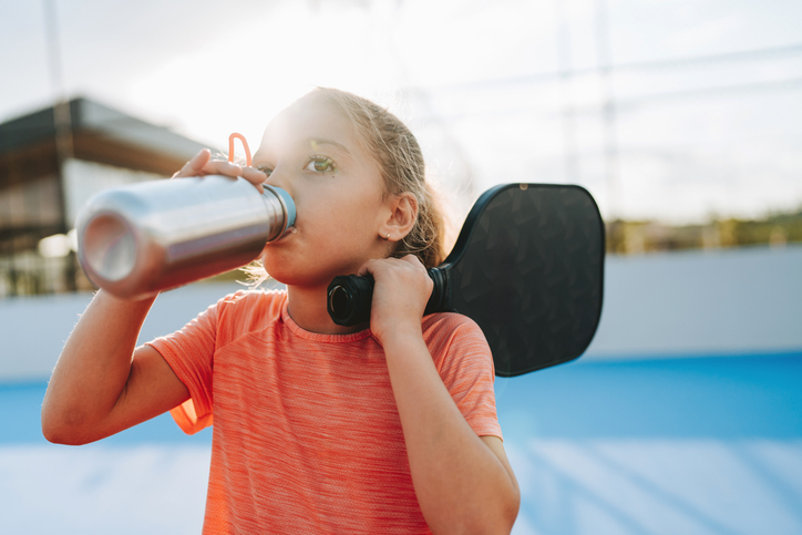 Young preteen drinking water during a game of paddleboard